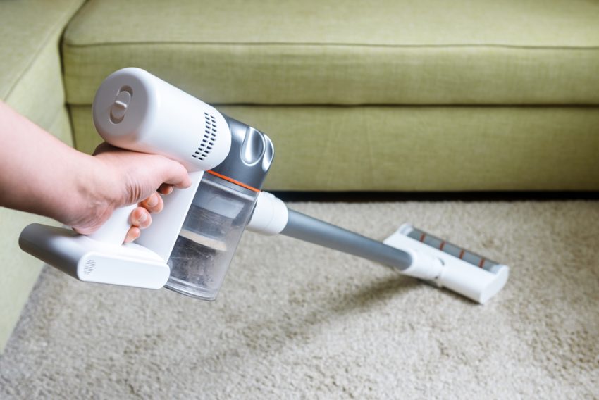 Wireless vacuum cleaner used on carpet in room. Housework with n