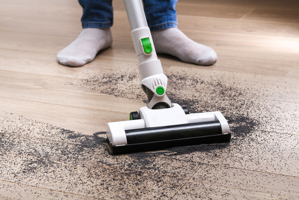 A man uses a bagless vertical cordless vacuum cleaner to clean floor.